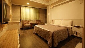 A hotel room with a bed, a desk, a chair, a television, and a window with curtains. - Taoyuan Hua Yue Hotel (Taoyuan City)