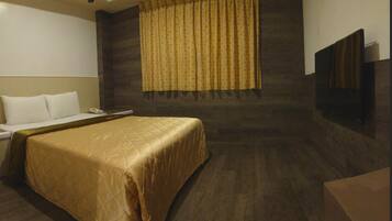 A hotel room with a bed, a bedside table, a phone, and a curtain.