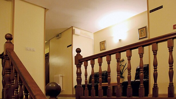 A wooden staircase with a balustrade leading to a landing. - Hotel América (Ferrol)