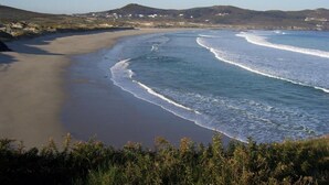 A beach with a curved shoreline, waves, and distant hills. - Hotel América (Ferrol)