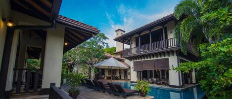 Una piscina al aire libre, sillones reclinables de piscina