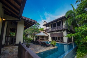 A pool area with lounge chairs, a covered seating area, and a two-story building with balconies. - Sergeant House (Unawatuna)