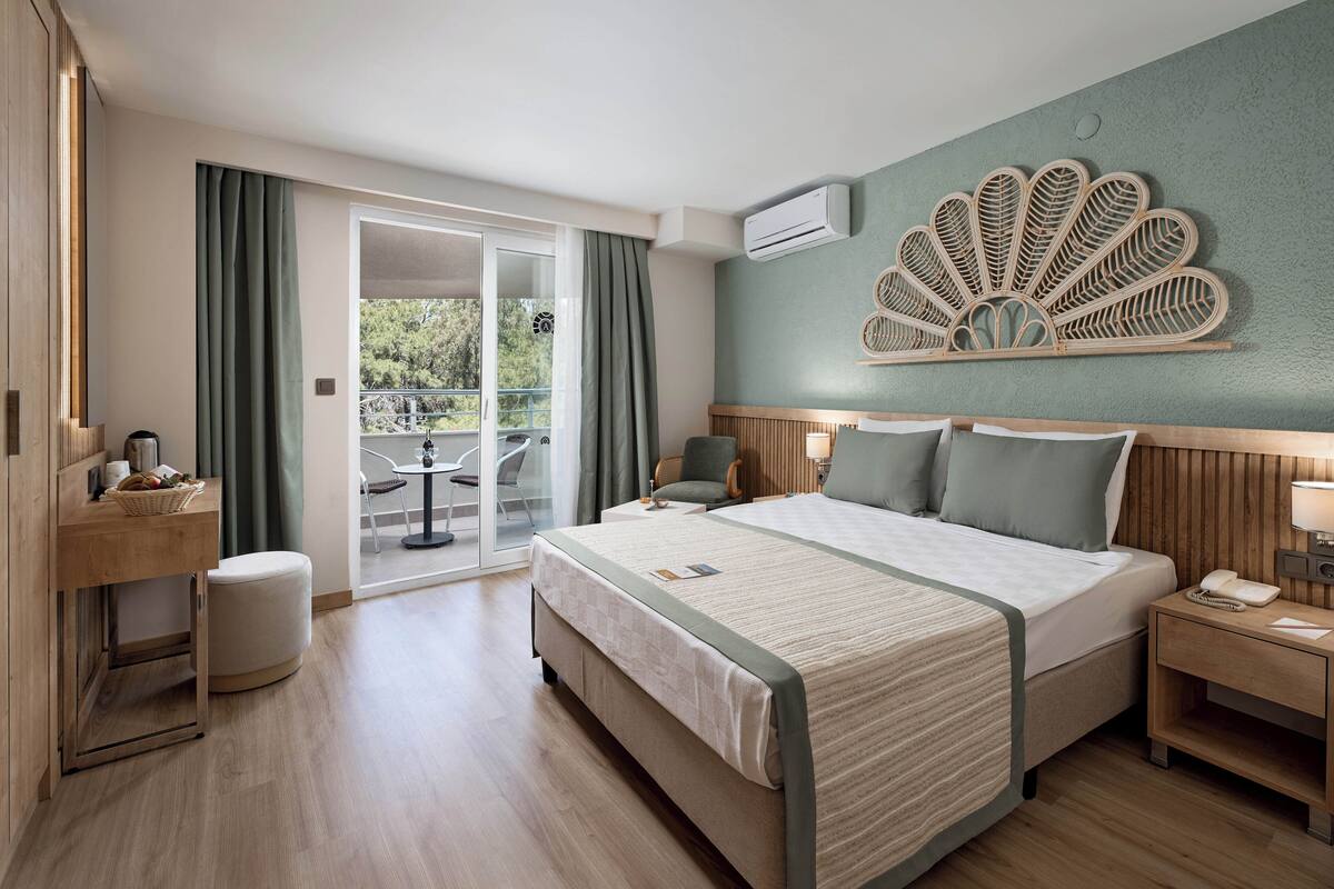 Een hotelkamer met een bed, nachtkastje en uitzicht op het landschap.