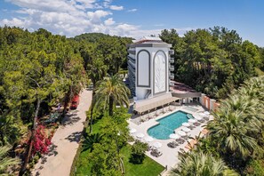 Un resort con piscina, sillones de descanso y una torre con balcón.