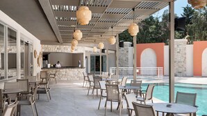Eine Terrasse im Freien mit Tischen und Stühlen, einem Pool und einer Steinmauer.