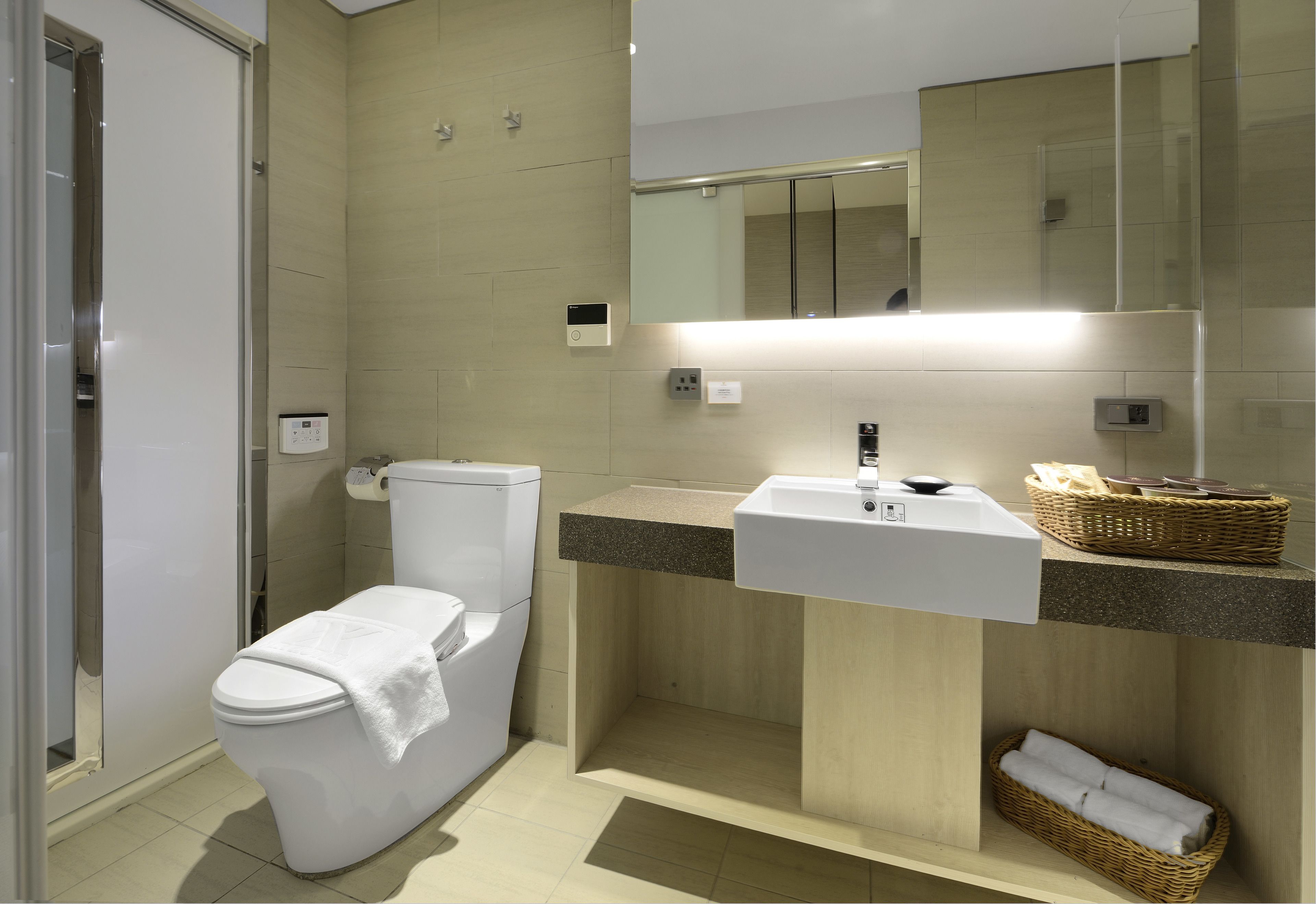 Un baño moderno con inodoro, lavamanos y espejo.