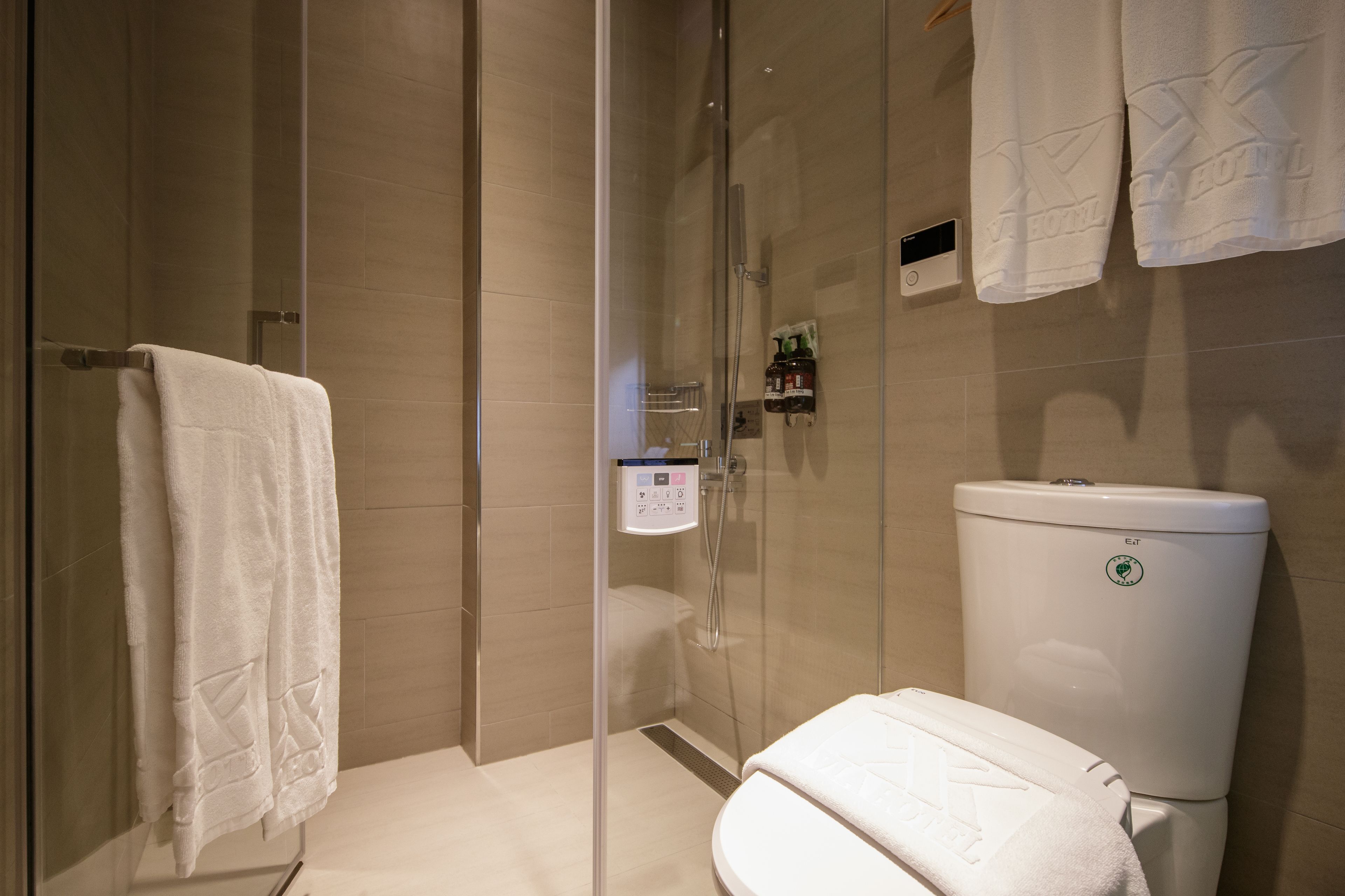 A modern bathroom with a glass-enclosed shower, a toilet, and a towel rack.