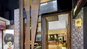 Ingresso moderno di un hotel con porta in vetro, una reception e una segnaletica che indica il terzo piano.