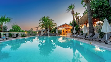 Una piscina al aire libre, sombrillas, sillones reclinables de piscina