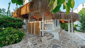 A thatched-roof outdoor area with a stone floor, a wooden bench, and a small table with a basket. - Golden Lighthouse Hotel (Kas)