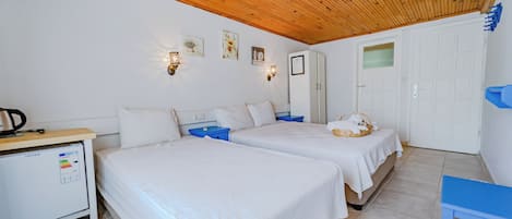 A bedroom with two beds, a wardrobe, a desk with a computer, and a small table.
