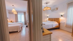 A hotel room with two beds, a wooden nightstand, a ceiling fan, and a window with blinds. - Golden Lighthouse Hotel (Kas)