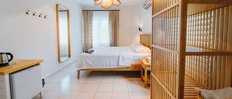 Habitación de hotel con cama, escritorio, espejo, lámpara colgante y un separador de madera.