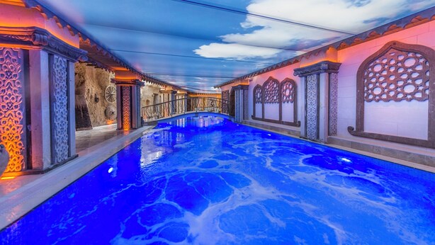 Ein Innenpool mit aufwendigen architektonischen Details und einem klarblauen Himmel, der durch die Decke sichtbar ist.