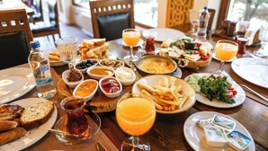 Ein Esstisch mit verschiedenen Speisen und Getränken, darunter Brot, Käse und ein Glas Orangensaft.