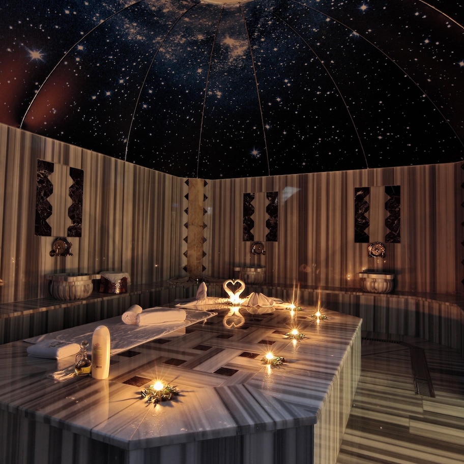 A room with a starry ceiling, a curved seating area, and a central table with candles and a heart-shaped decoration.