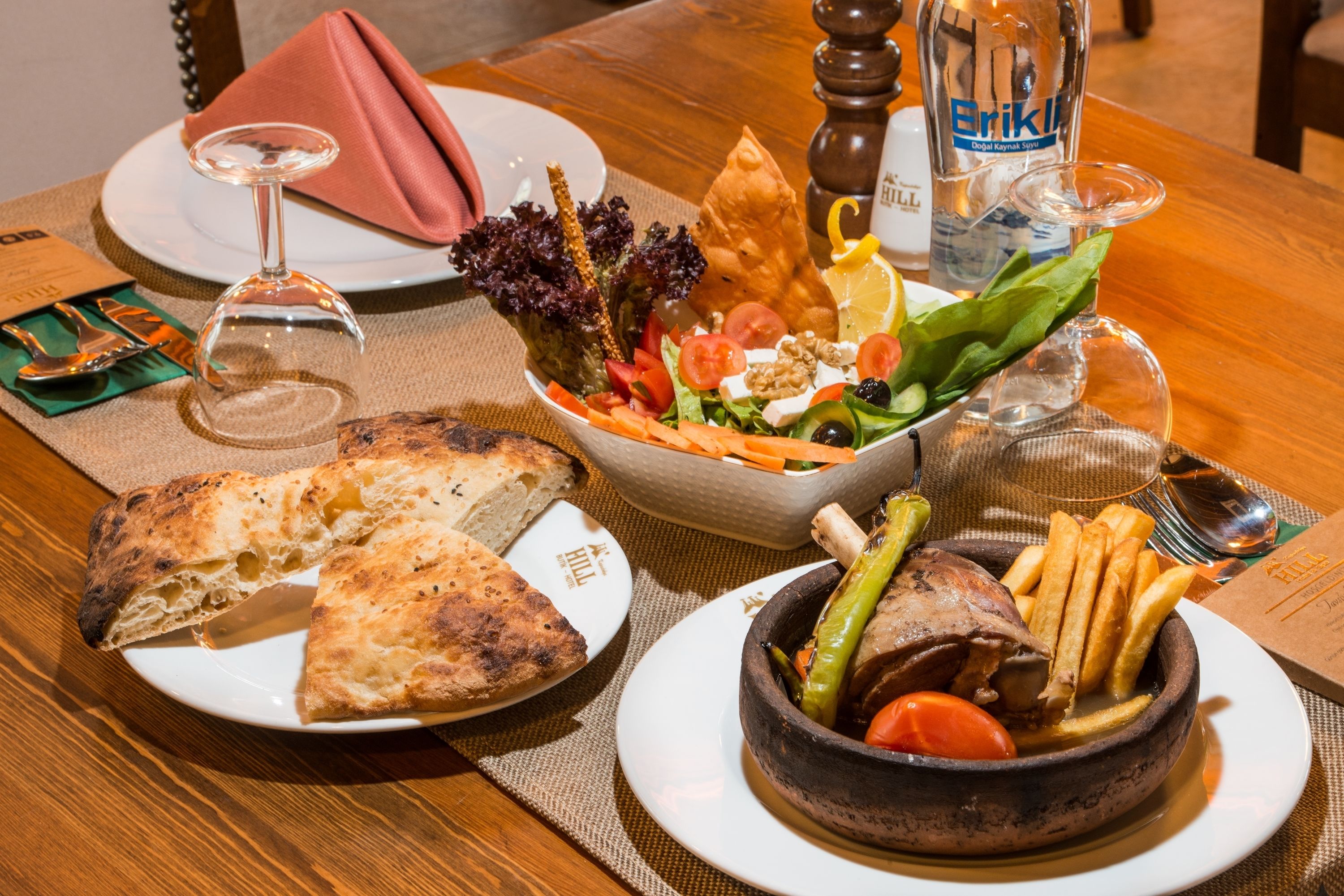 A dining table with a variety of dishes including bread, salad, and a bowl of meat.