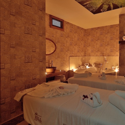 A hotel room with two beds, a large mirror, a sink, and a ceiling with a tree design.