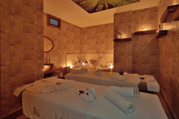 Quarto de hotel com duas camas, um espelho grande, uma pia e teto com desenho de árvore.