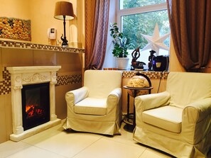 Cozy living room with a fireplace, armchairs, and a side table, featuring a globe and a star ornament.