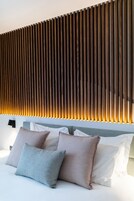 Un dormitorio moderno con cama, almohadas y cabecera de listones.