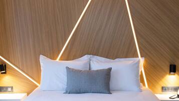 A modern hotel room with a large bed, wooden panel wall, and geometric light fixtures.