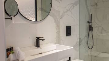 Un baño moderno con un lavamanos blanco, grifo negro y dos espejos redondos.