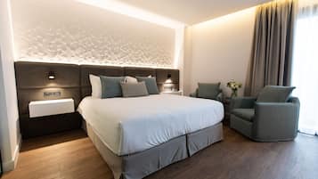 Une chambre d’hôtel moderne avec un grand lit, une table de chevet, une chaise et un panneau décoratif mural.