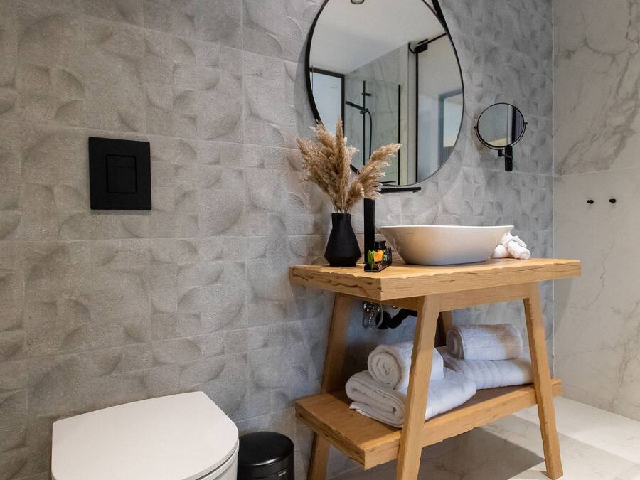 A modern bathroom with a white toilet, a wooden vanity with a sink, and a mirror above the vanity.