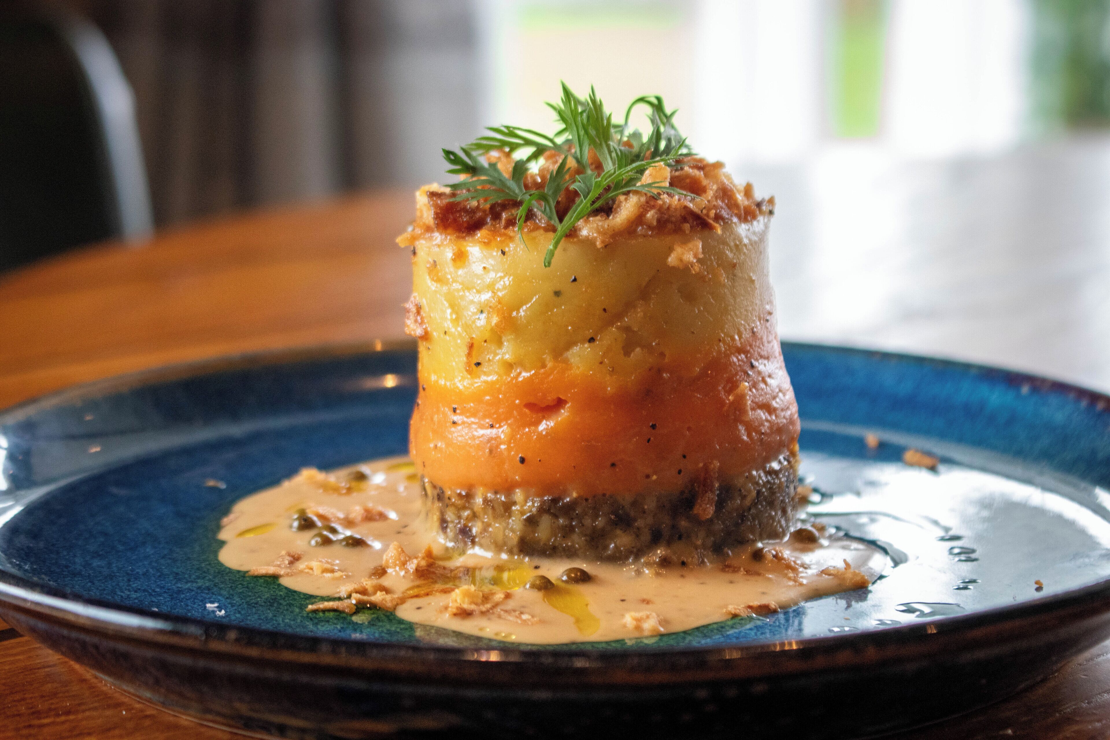 En rätt med en krämig sås, garnerad med örter, serverad på en blå tallrik.