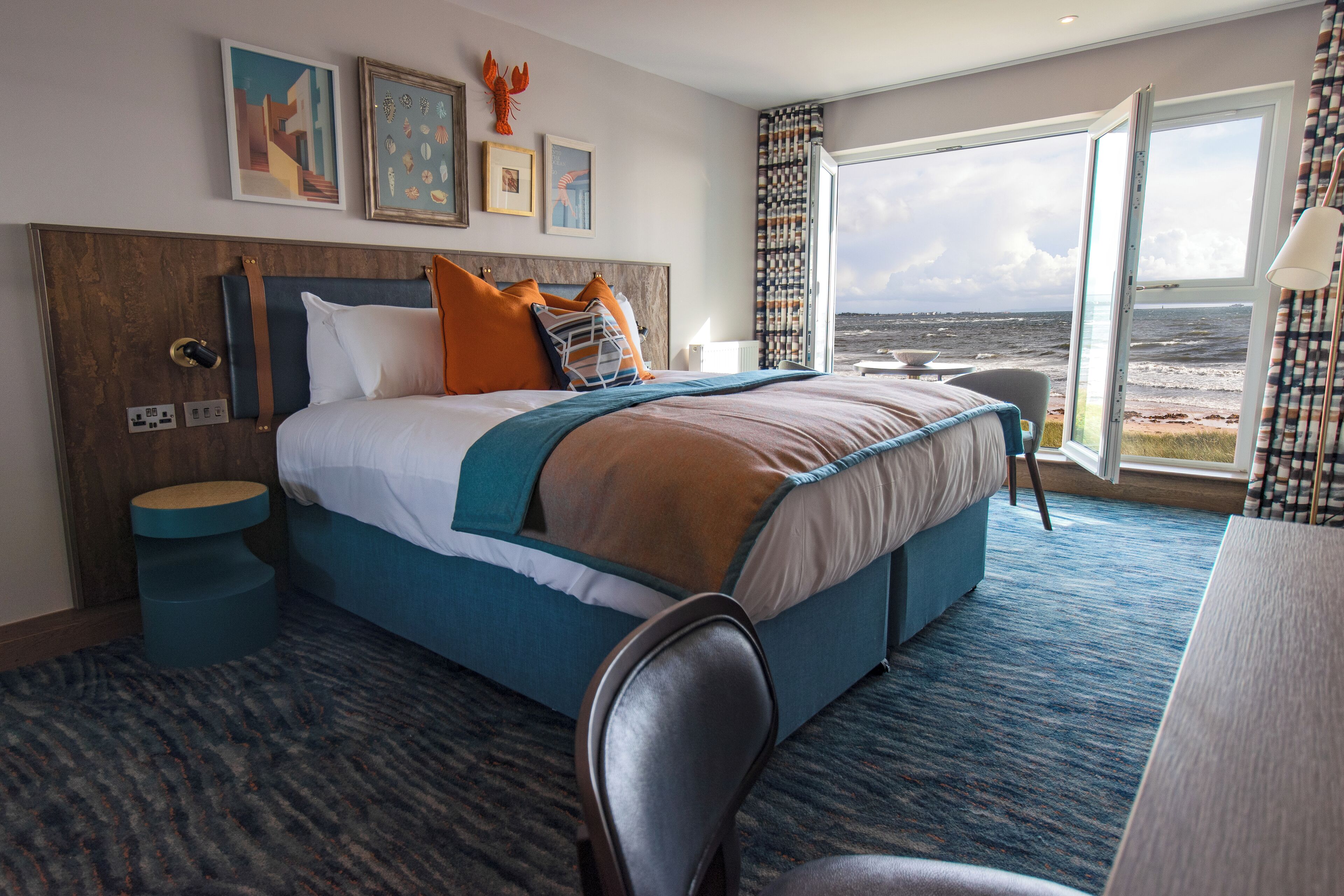 Habitación de hotel con una cama grande, un escritorio y vista al mar.