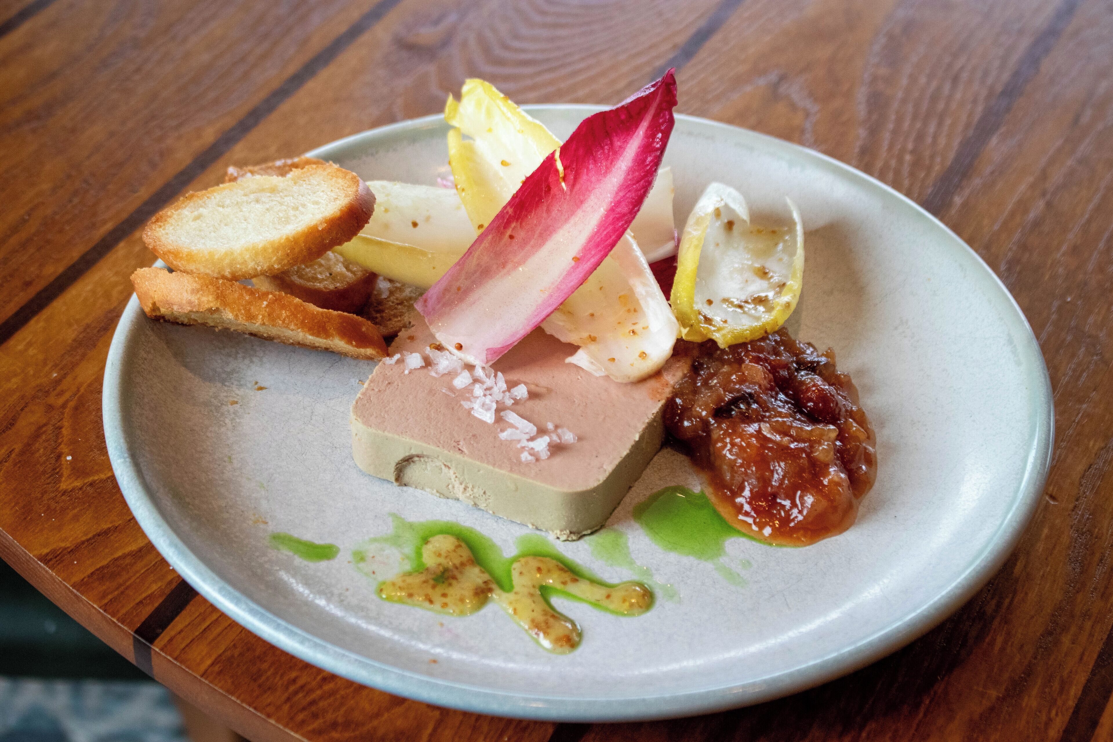 Een bord eten met verschillende elementen, waaronder brood, een roze toetje en garnering.
