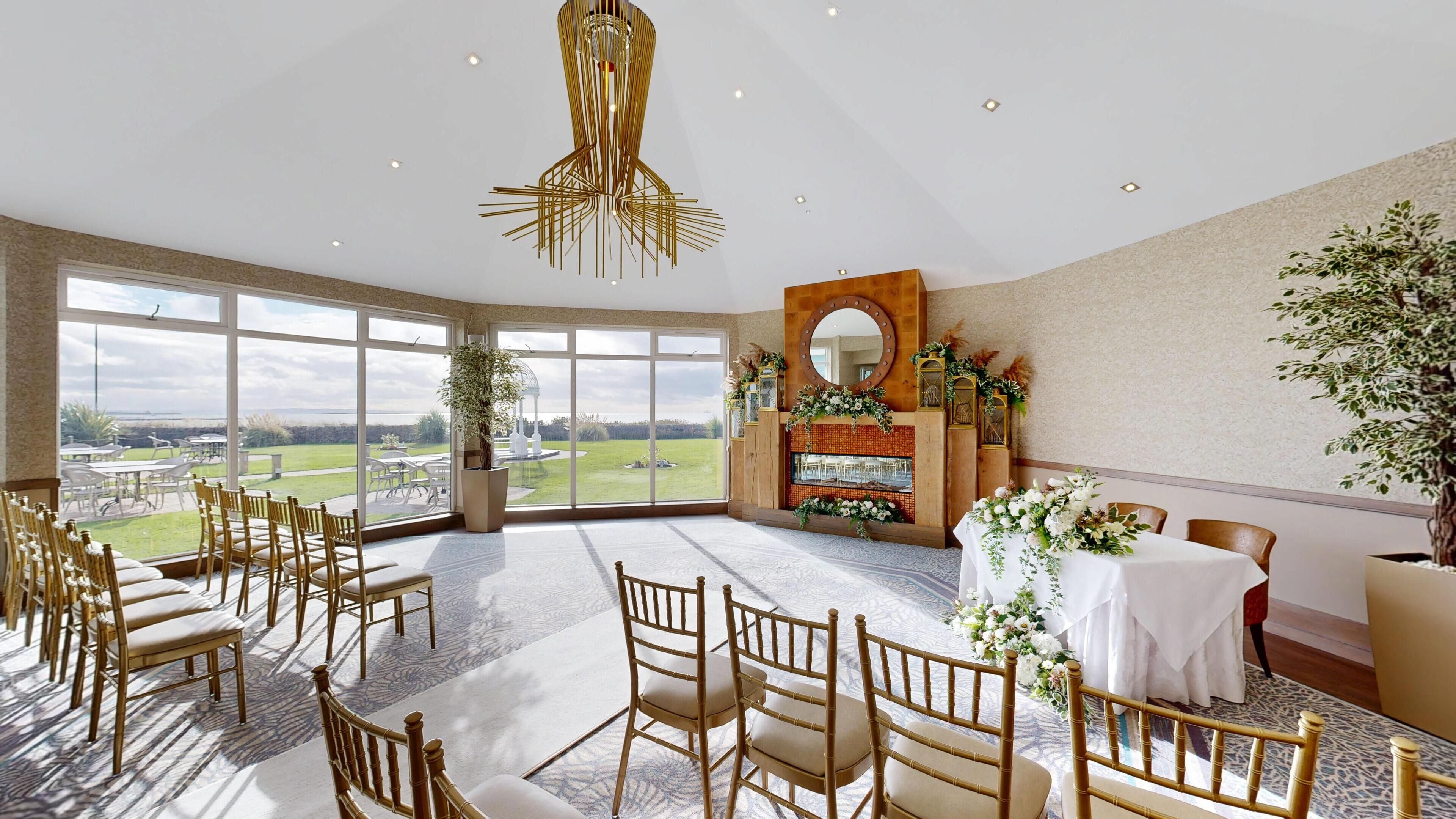 A spacious room with large windows, a central floral arrangement, and a high ceiling with a unique light fixture.