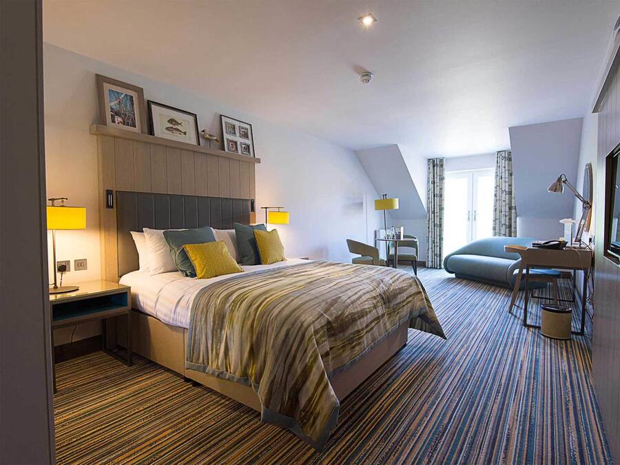 Une chambre d’hôtel moderne dotée d’un grand lit, d’un bureau et d’un coin salon confortable.