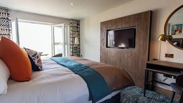 A modern hotel room with a large bed, a desk, a TV, and a view of the outdoors.