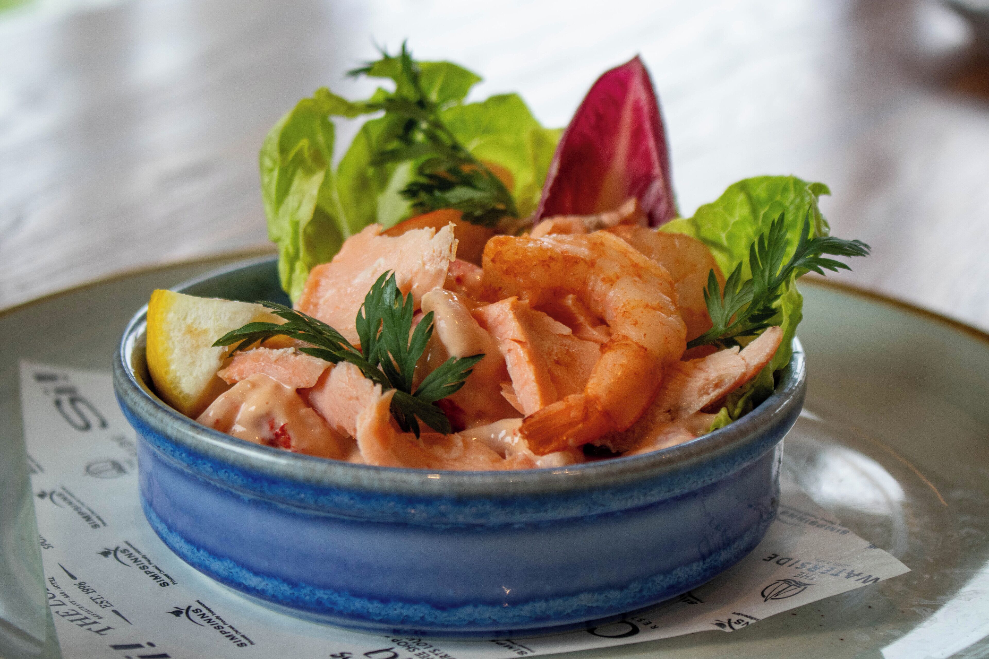 Ensalada de salmón en un plato, con adorno de limón y perejil.