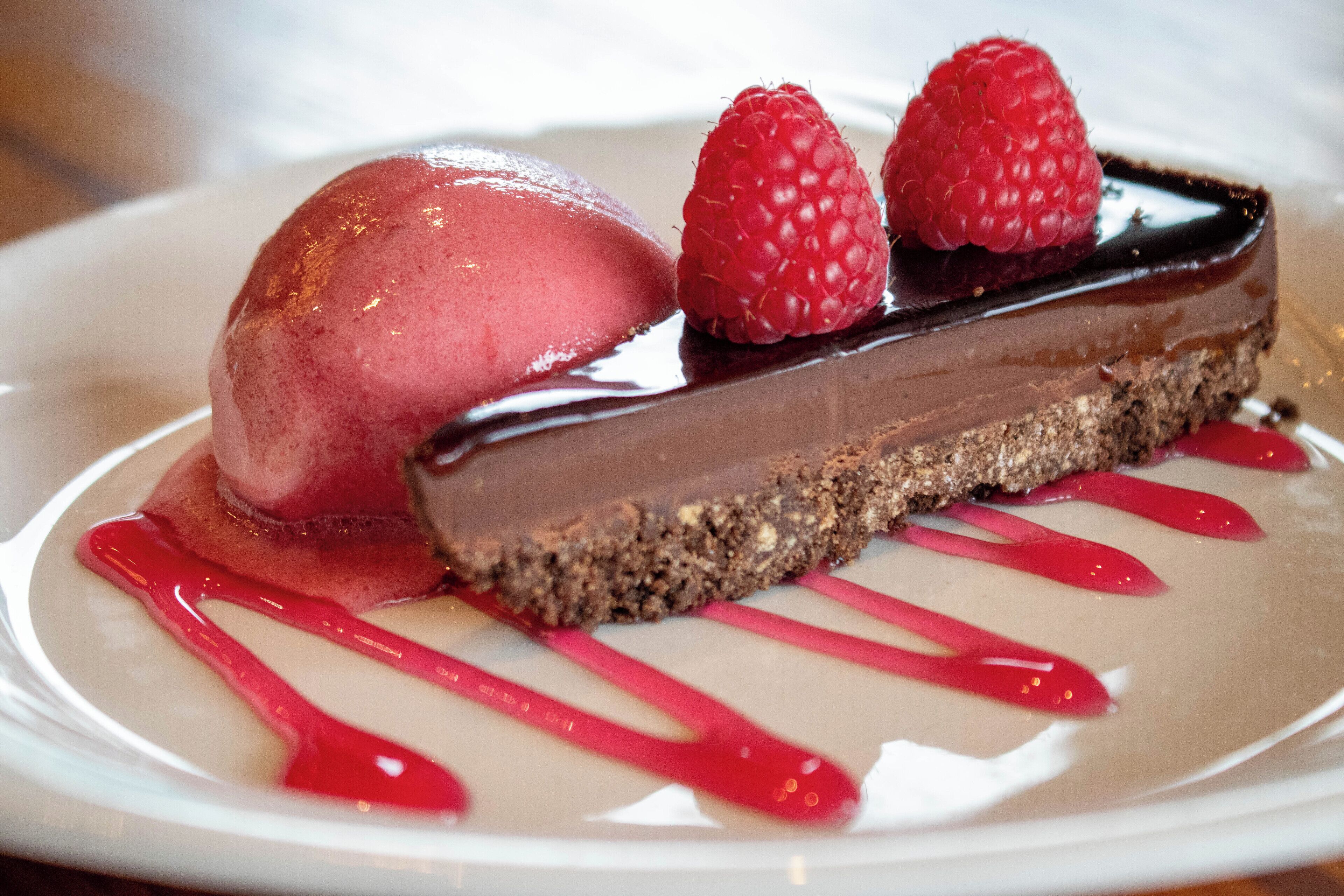 A dessert with a chocolate layer and raspberries on a plate.
