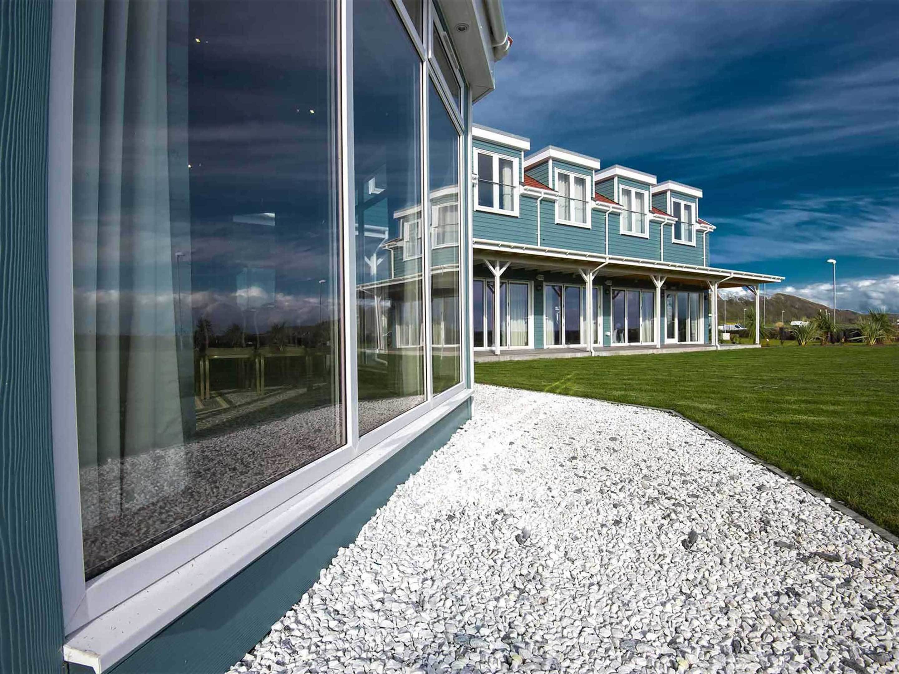 Una casa moderna de dos pisos con ventanas grandes y un porche cubierto.