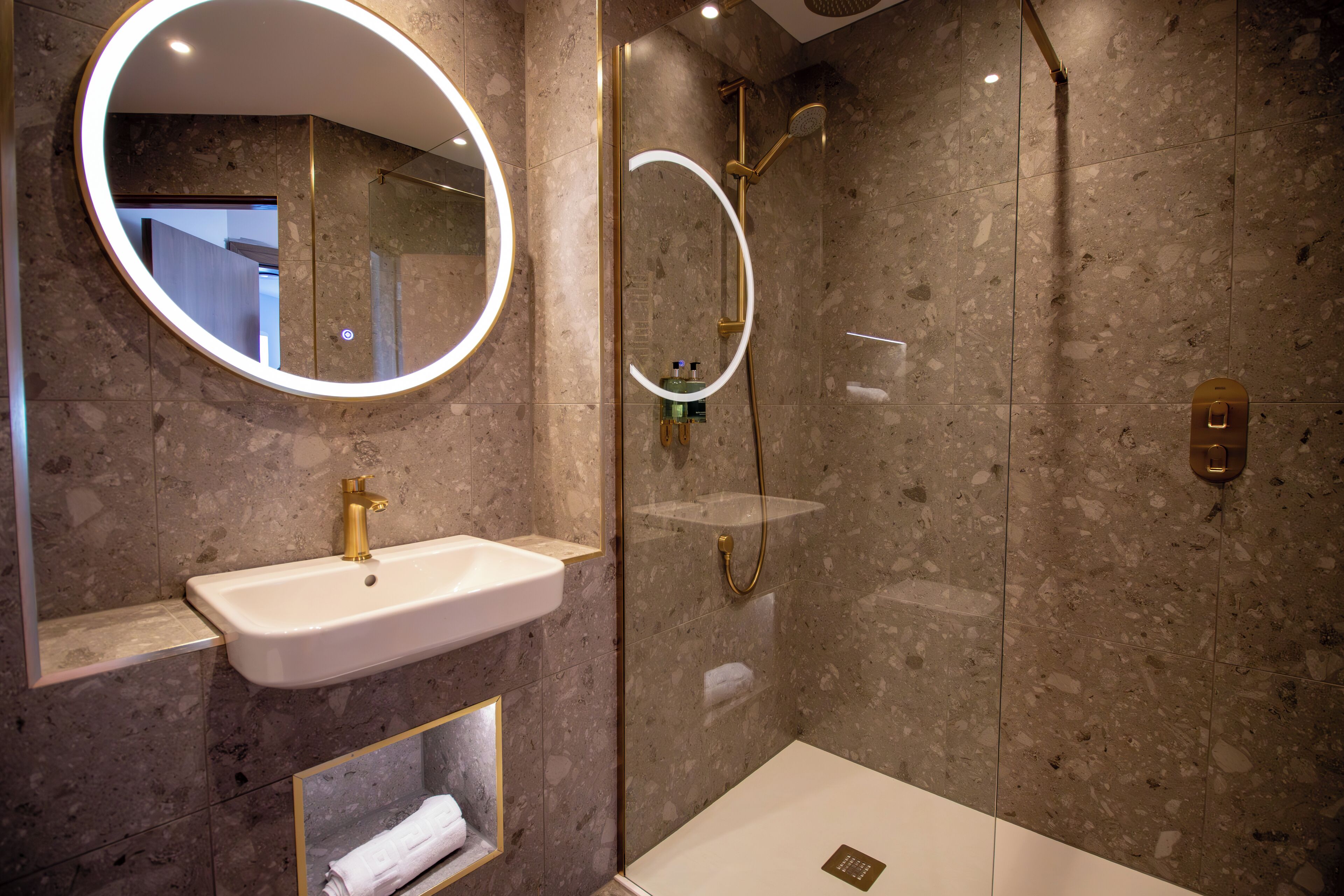 Un baño moderno con lavamanos, espejo y ducha.