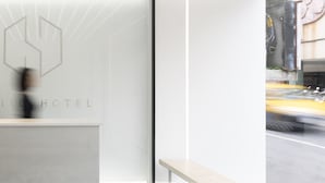 Una recepción de hotel moderna con un diseño minimalista, que presenta un logotipo y el nombre 'SWITCH HOTEL' en la pared de vidrio.