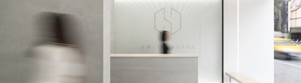 A modern hotel reception with a minimalist design, featuring a logo and the name 'SWITCH HOTEL' on the glass wall. - Swiio Hotel Daan (Taipei)