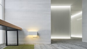 Un interior moderno con un diseño minimalista, que presenta una mesa de madera, una alfombra verde y un aplique de pared.