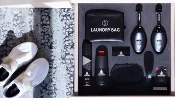 A neatly arranged set of personal care items including a laundry bag, a hairbrush, and a bottle of shampoo, placed on a textured surface.