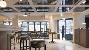 Interior de restaurante con techos altos, mobiliario de madera y ventanas amplias.