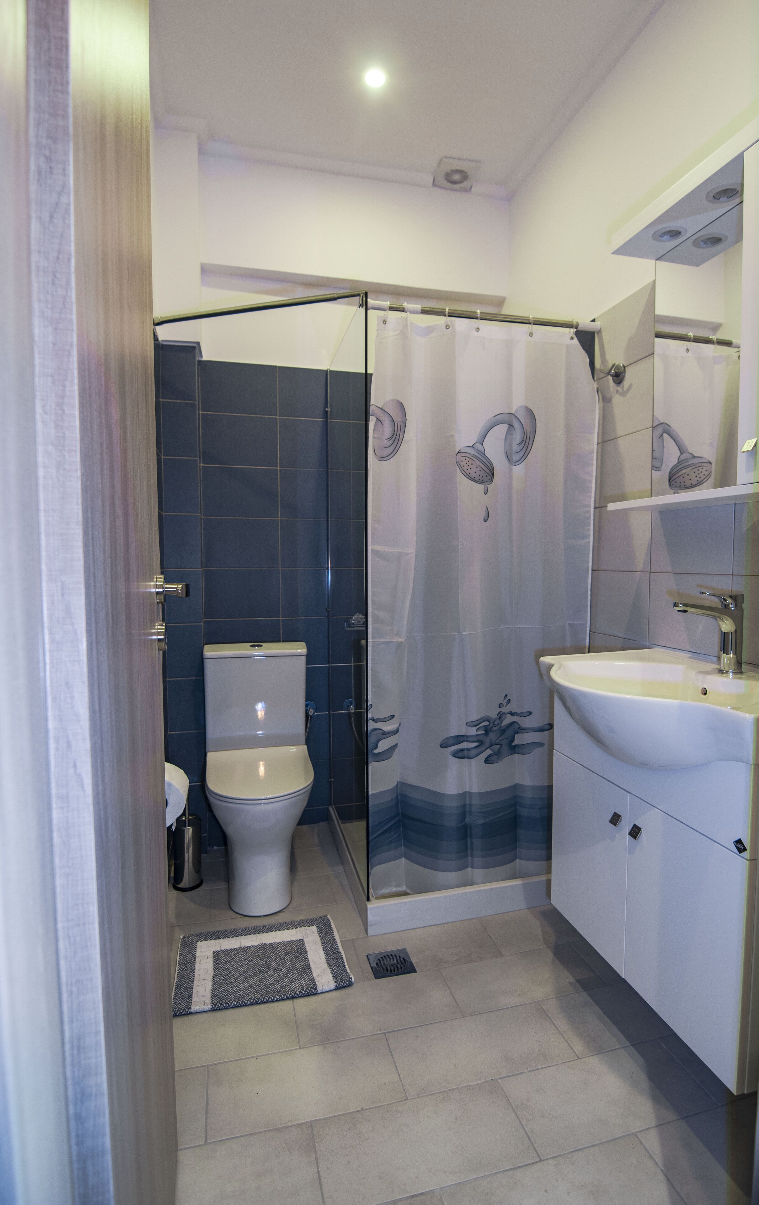Bagno con doccia, WC, lavandino e divisorio in vetro.