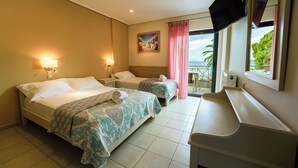 A hotel room with two beds, a desk, a TV, and a balcony with a view. - Nefeli Studios (Dorida)
