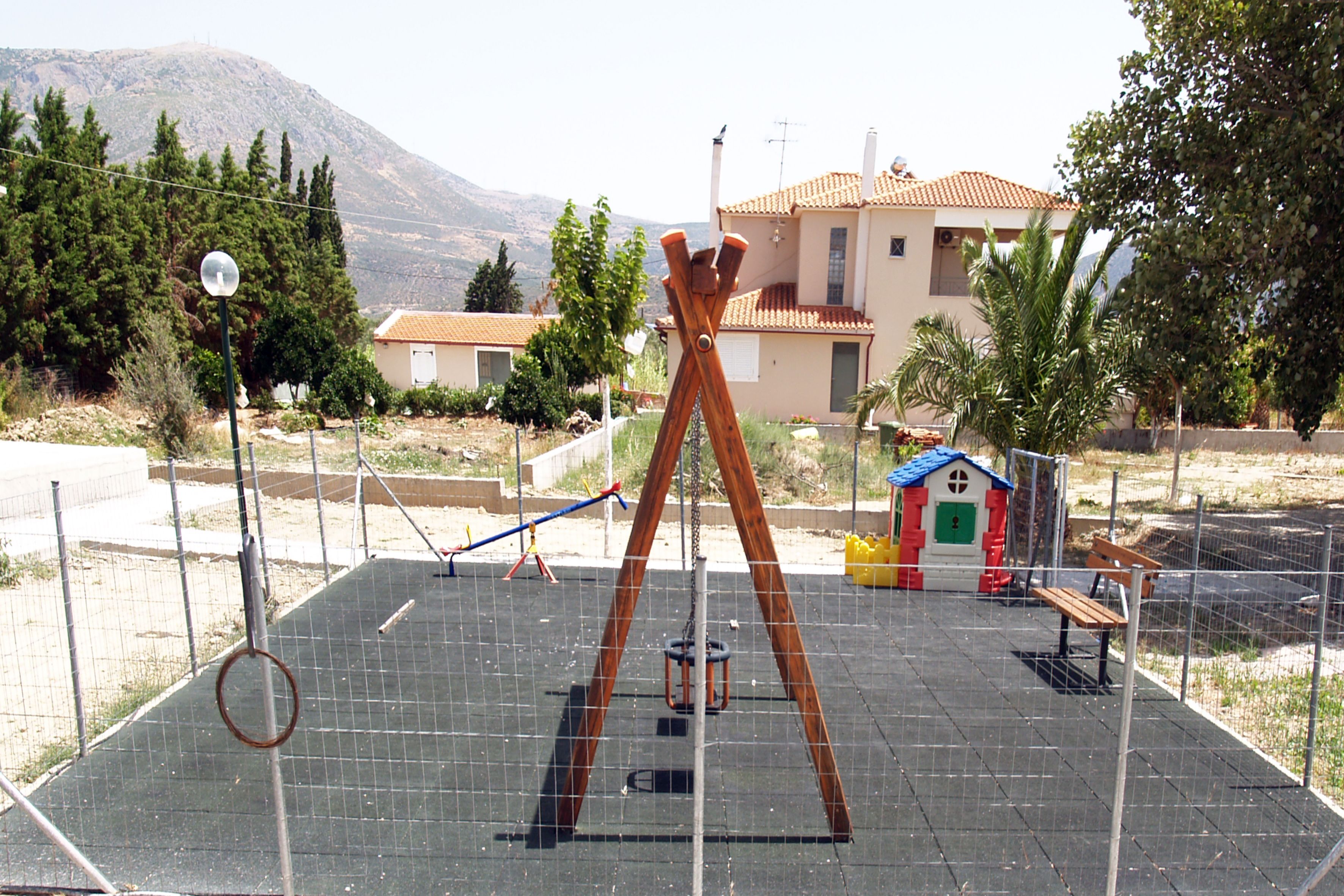 A playground with swings, a slide, and a small playhouse.