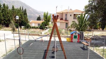 A playground with swings, a slide, and a small playhouse.