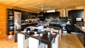 A modern kitchen with wooden ceilings, stainless steel appliances, and a central island with seating. - A Casa do Tio Tenente (Serta)