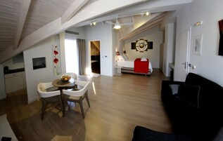 Un apartamento moderno con comedor, sala de estar con sofá negro, cocina y dormitorio con pared de acento roja.